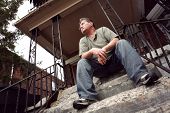 picture of man  - Middle aged man sitting on the steps of a house - JPG 