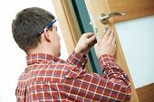 picture of industrial  - Male handyman carpenter at interior wood door lock installation - JPG 