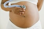 foto of medical  - Pregnant African woman holding stethoscope on belly - JPG 