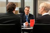picture of meeting  - Mature lawyer or notary with clients in his office in a meeting - JPG 
