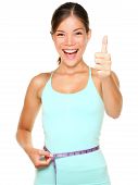 image of fitness  - weight loss woman smiling happy excited standing with measuring tape giving thumbs up success hand sign isolated on white background - JPG 