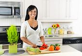 image of interior  - Smiling black woman cutting vegetables in modern kitchen interior - JPG 