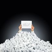 stock photo of finance  - Person under crumpled pile of papers with hand holding a help sign - JPG 