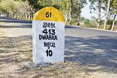 image of incorporate  - Rural landscape in Gujarat India incorporating 413 kilometers to Dwarka milestone and land mark on the coastal road to Dwarka and religious town for Hindus - JPG 
