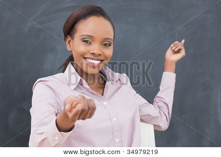 Picture or Photo of Black teacher smiling while showing the blackboard in a classroom