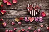 stock photo of holidays  - Word Love with Heart shaped Valentines Day gift box on old vintage wooden plates - JPG 