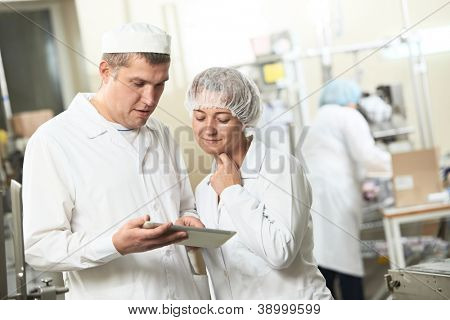 Picture or Photo of Two pharmaceutical workers discussing manufacture project with tablet computer at pharmacy industry