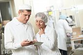 stock photo of industrial  - Two pharmaceutical workers discussing manufacture project with tablet computer at pharmacy industry - JPG 